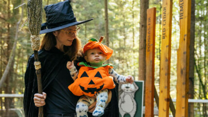 Mother dressed up in witch halloween costume with baby dressed in pumpkin costume during Canyon Frights at Capilano Suspension Bridge Park