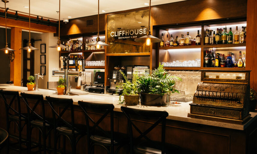 the bar of the Cliff House Restaurant warmly lit with a fully stocked bar