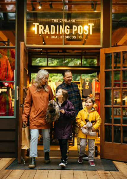 A family exits the Trading Post Gift Shop, with kids happily holding stuffed animals, showcasing the excitement and enjoyment of souvenir shopping at Capilano Suspension Bridge Park