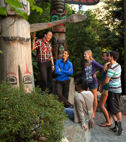 Tour guide with group of guests at Kia'palano totem poles at Capilano Suspension Bridge Park