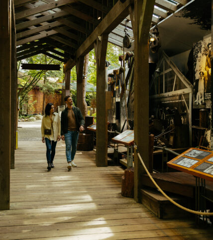 A couple strolls through the Story Centre, while looking at the historical displays, immersed in the fascinating narratives of Capilano Suspension Bridge Park's past.
