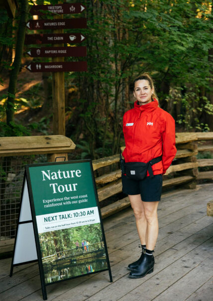 Nature Guide team member standing at nature tour sign